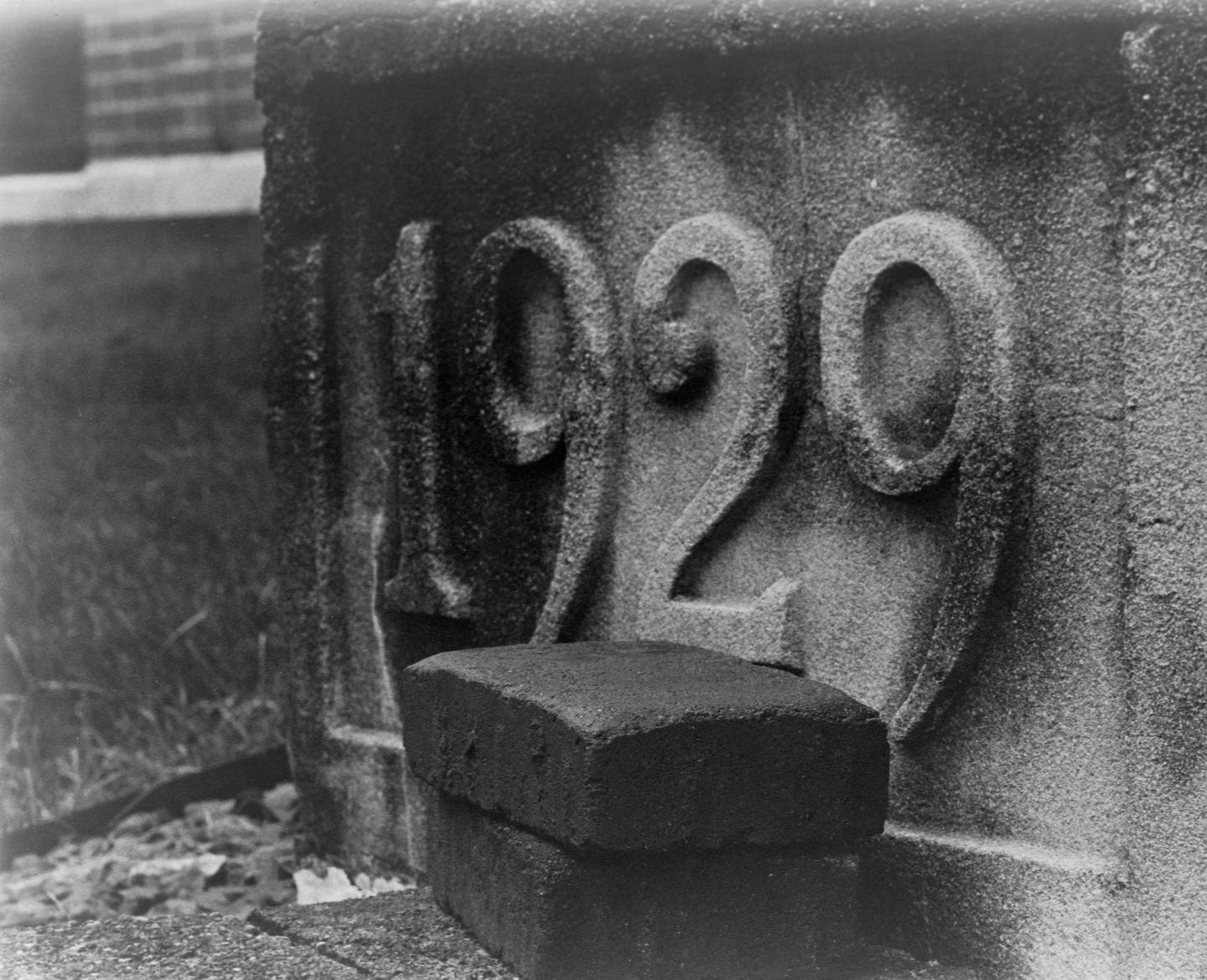 The numbers "1929" are carved into a stone surface, with two bricks resting in front of them.