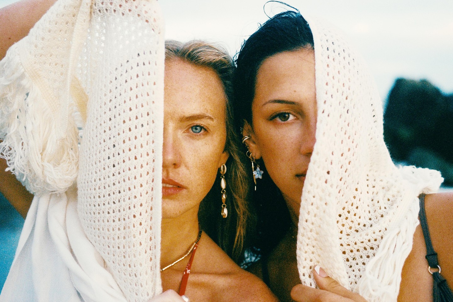 Two women with scarves covering parts of their faces look directly at the viewer.