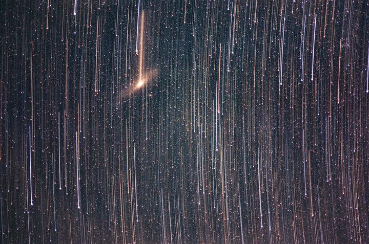 A long exposure photograph captures star trails and the Andromeda galaxy.