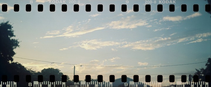 A wide shot of a cloudy sky with trees and a utility pole visible at the bottom of the frame.