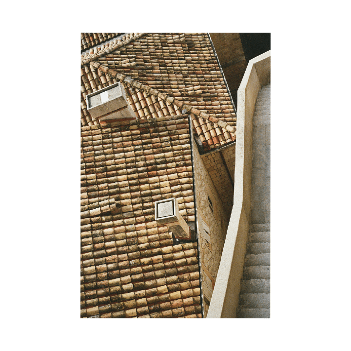 An aerial view shows a terracotta tiled roof next to a stone staircase and wall.