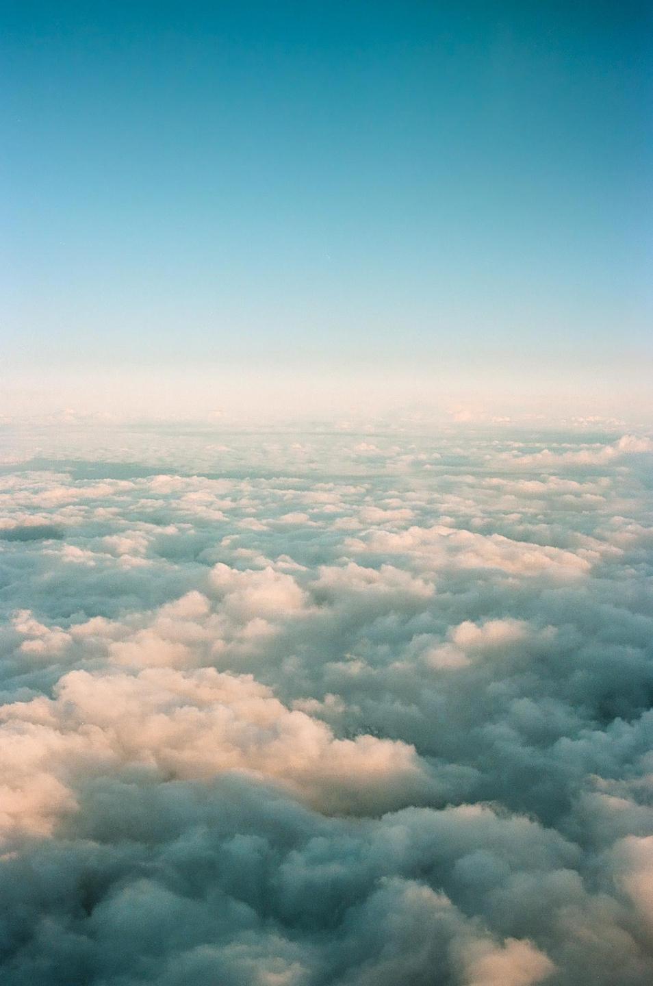 An aerial view shows a vast expanse of clouds under a clear sky.