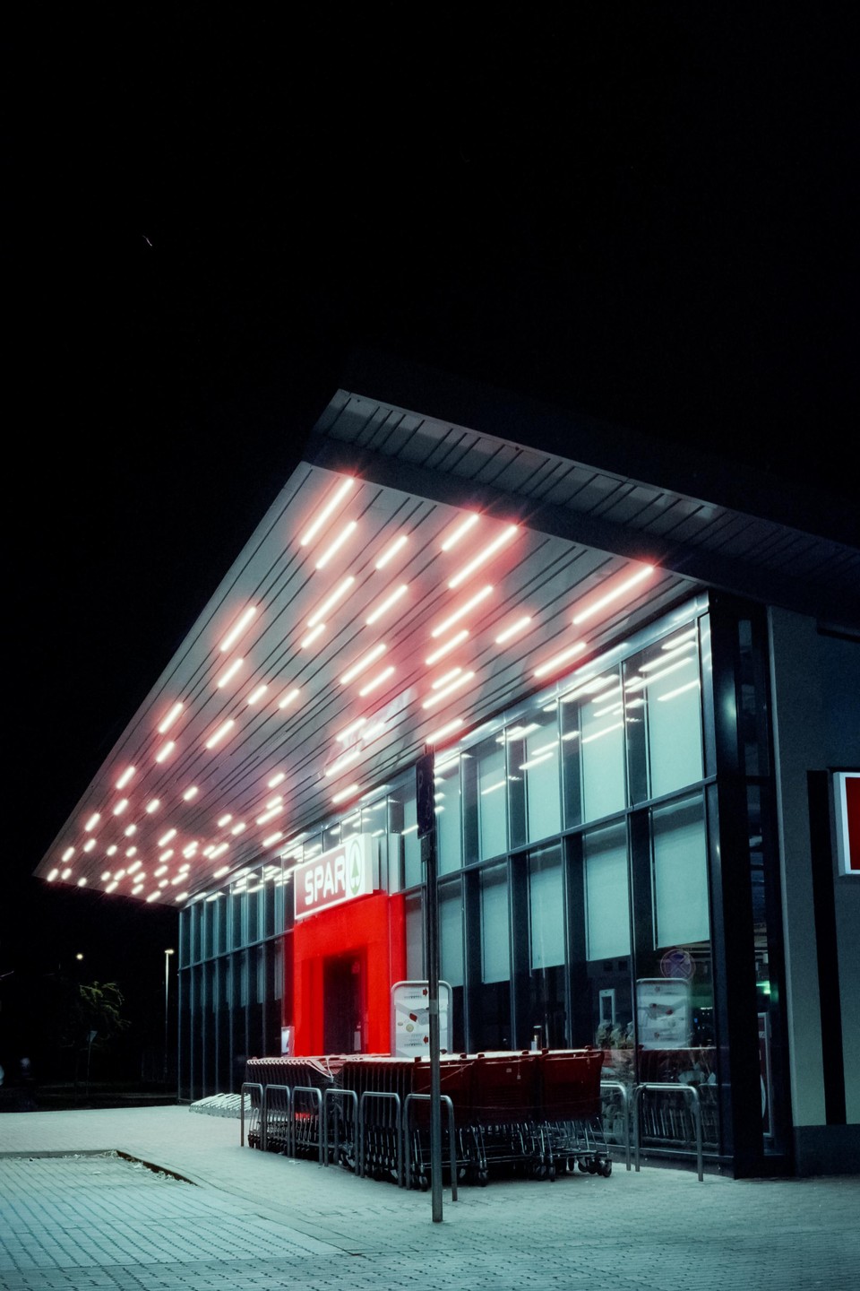 A Spar supermarket is illuminated by neon lights at night.