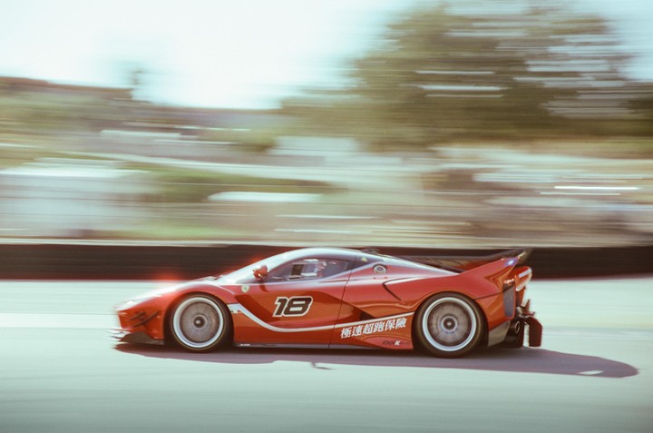 A red race car with the number 18 on its side speeds past a blurred background.
