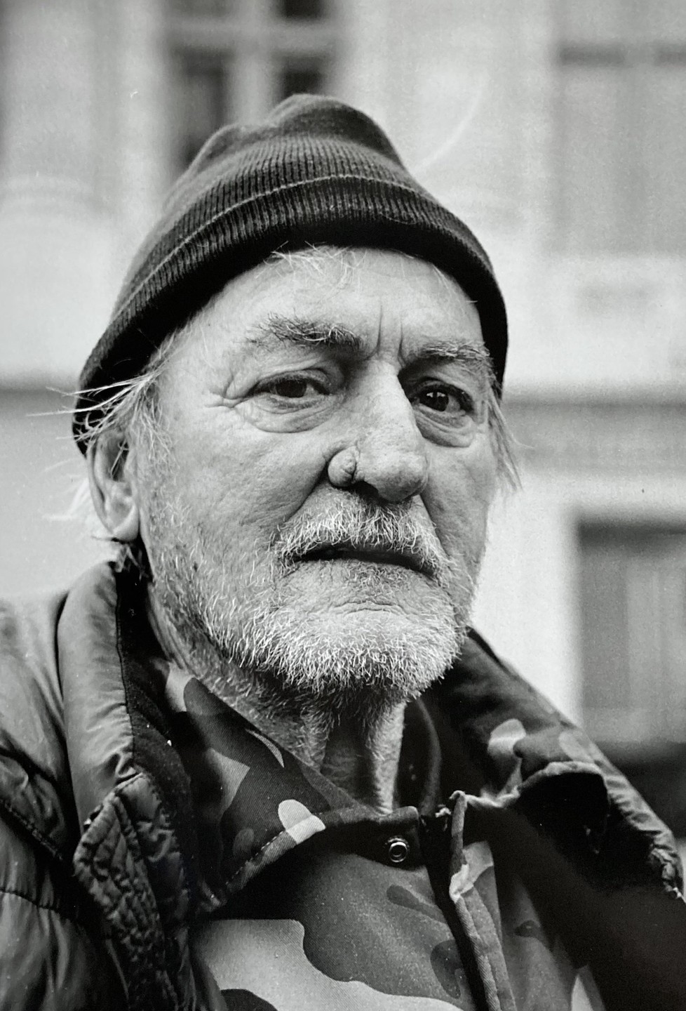 A man with a beard and a knit hat looks directly at the viewer.