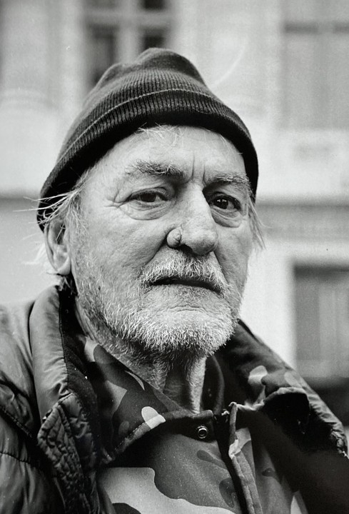 A man with a beard and a knit hat looks directly at the viewer.