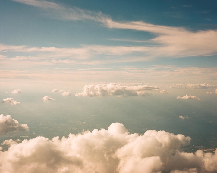 Clouds are visible from an aerial perspective, with a faint landscape visible below.