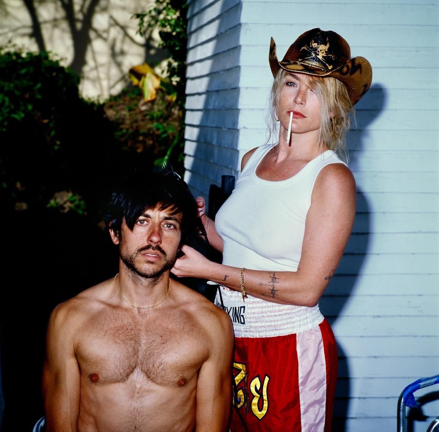 A woman in a cowboy hat and a man are posing for a portrait outdoors.