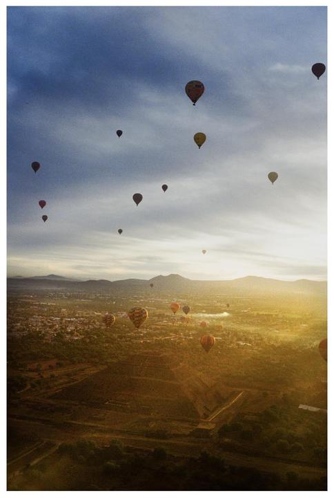Hot air balloons float above the ancient city of Teotihuacan at sunrise.