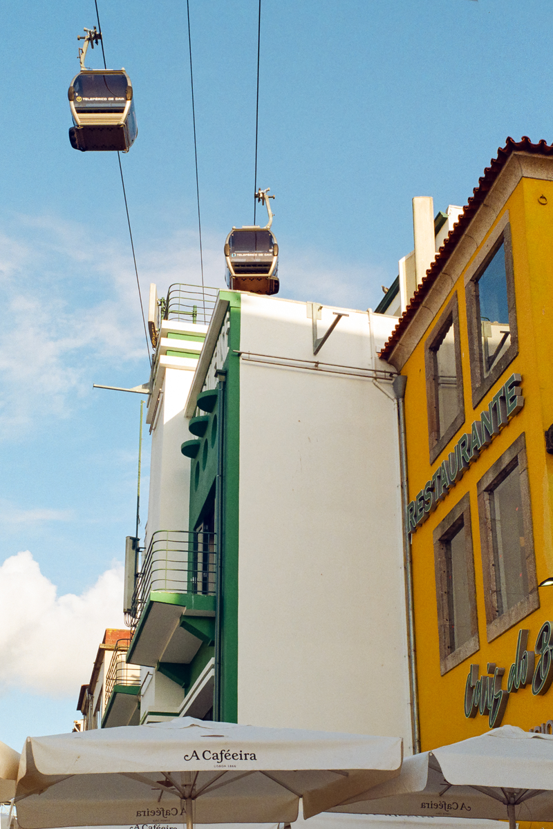 Two cable cars are visible above buildings with a bright blue sky in the background.