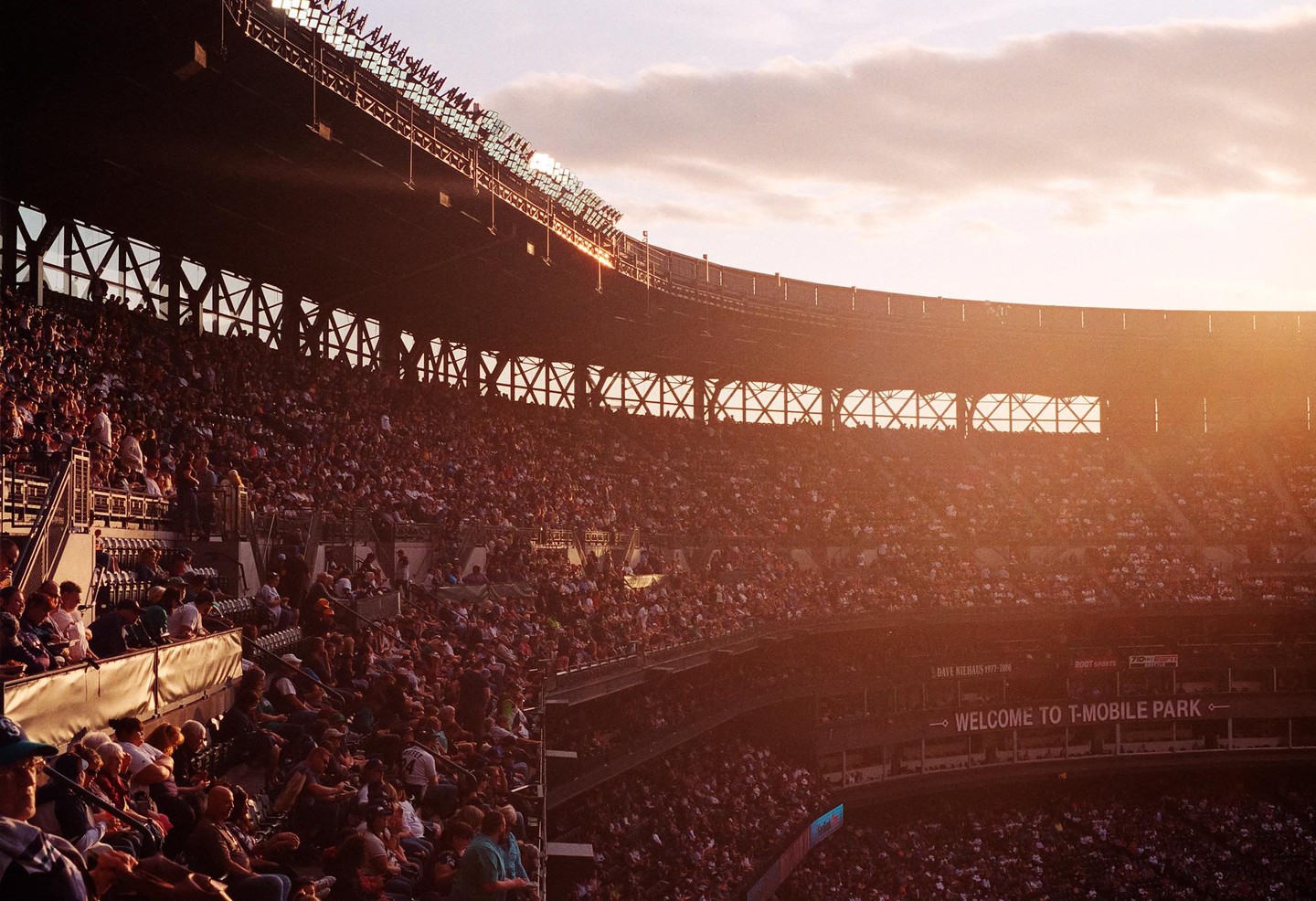 A stadium full of people is illuminated by the golden hour sun.