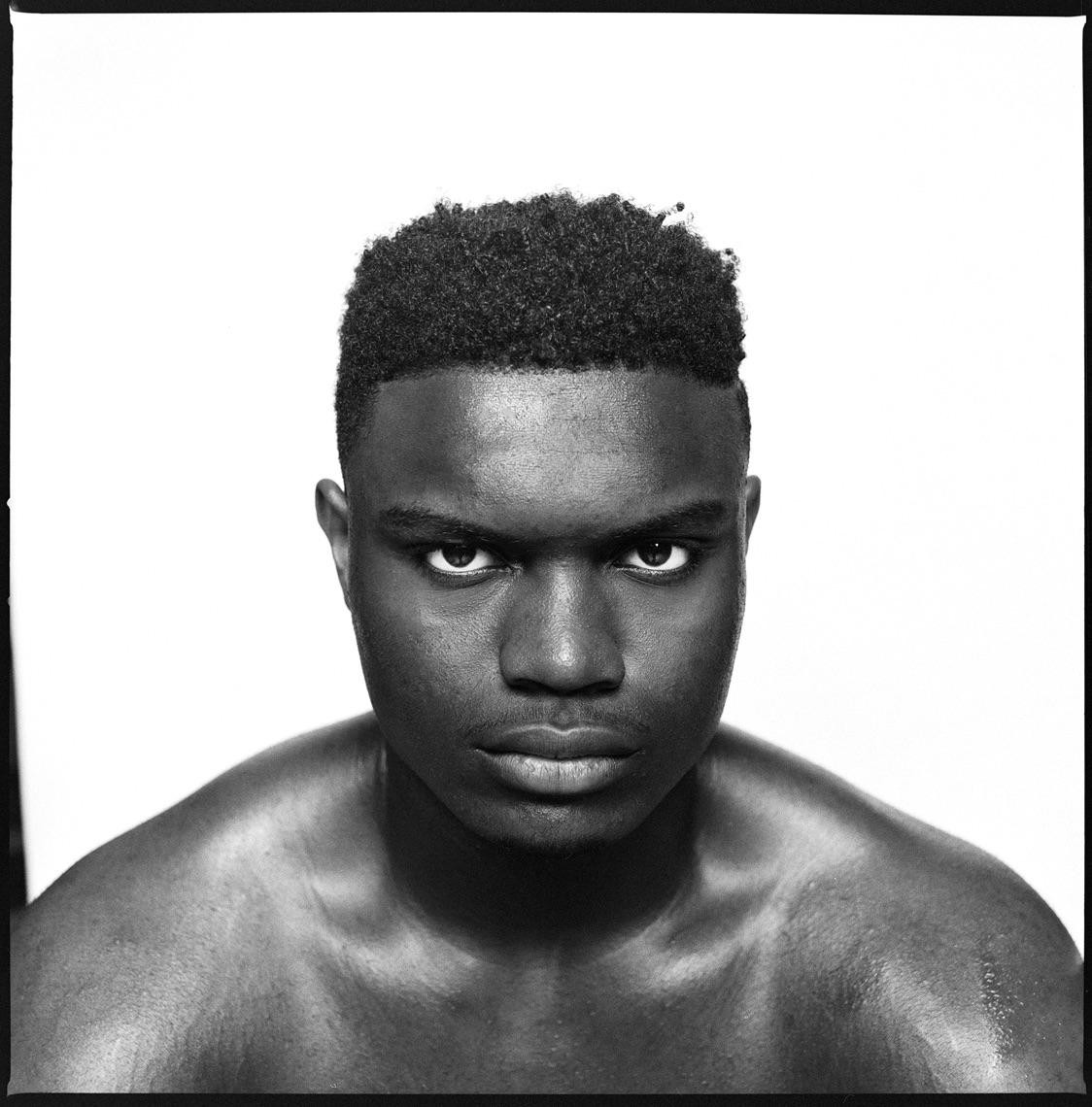 A man with short curly hair stares intensely at the viewer.