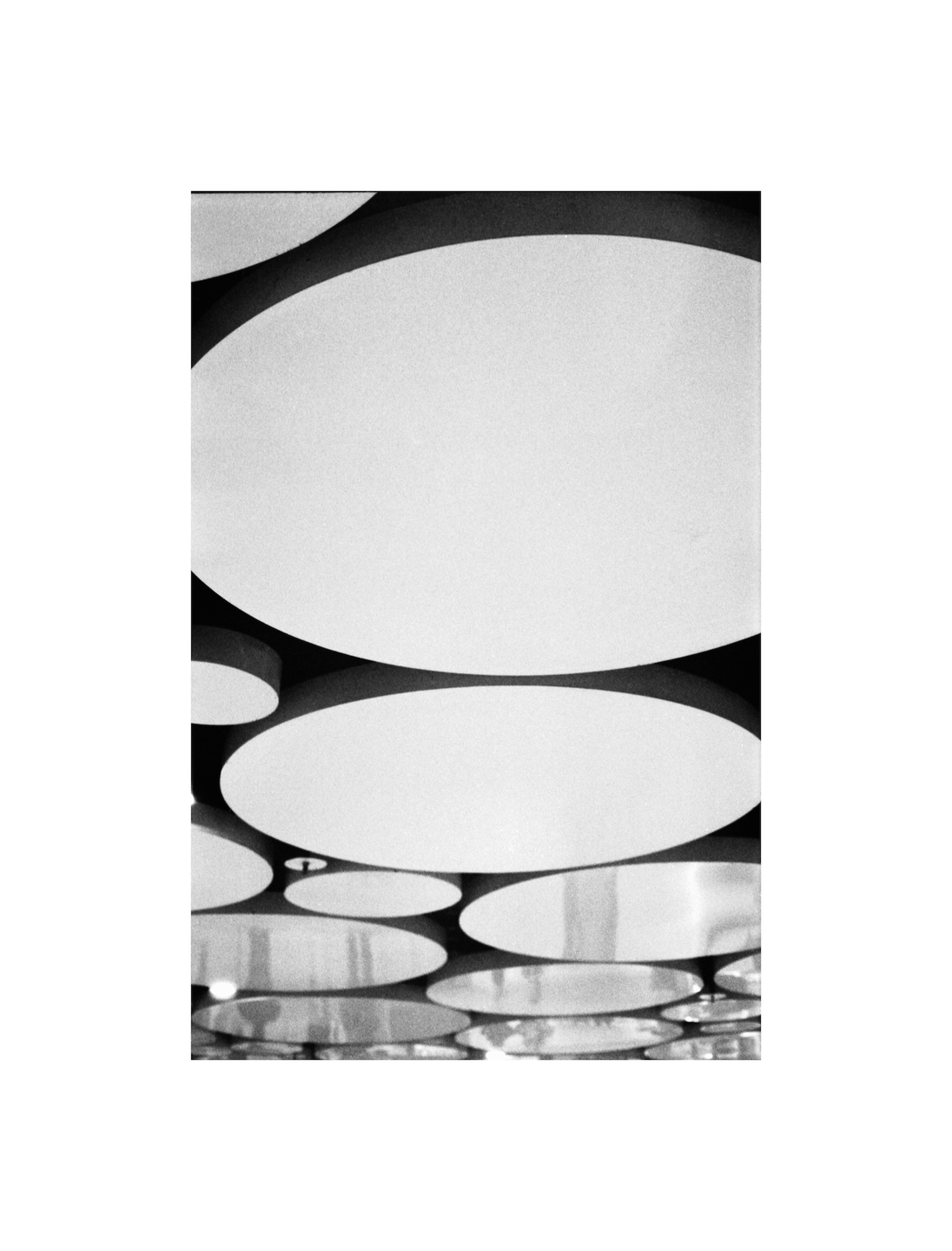 A black and white image shows a pattern of overlapping circles on a ceiling.