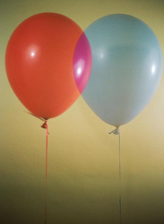 Two balloons, one red and one blue, overlap to create a magenta section in the middle.