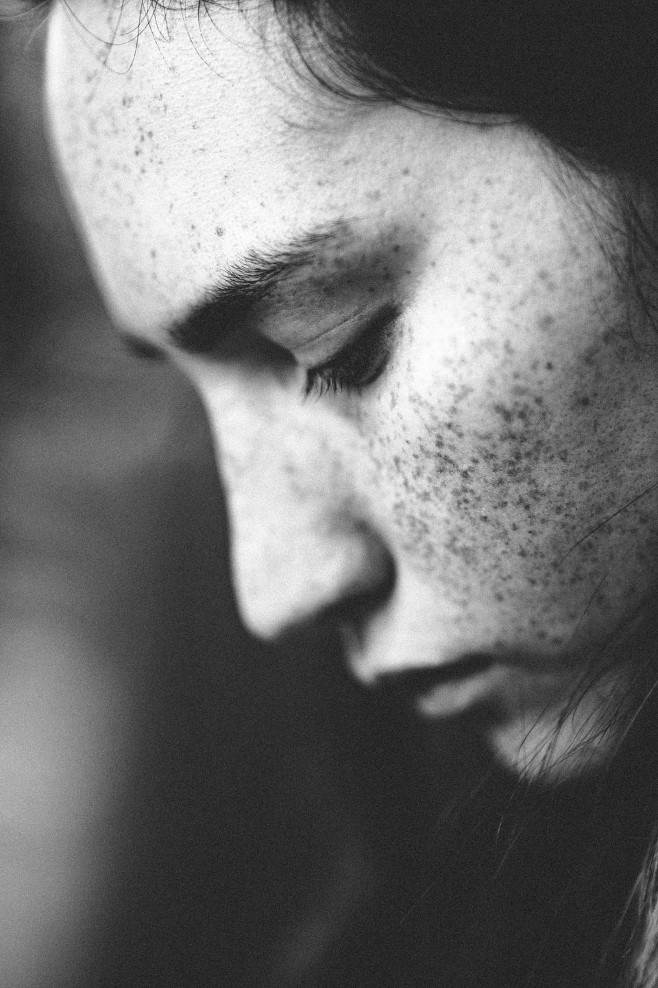 A woman with freckles and closed eyes is shown in profile.