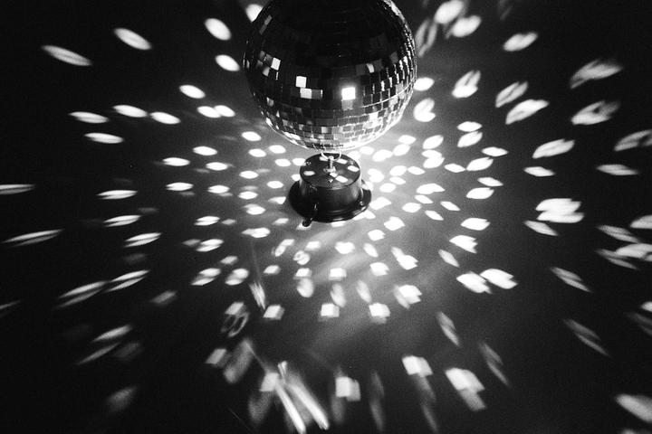 A disco ball hangs above a surface, casting numerous light reflections.