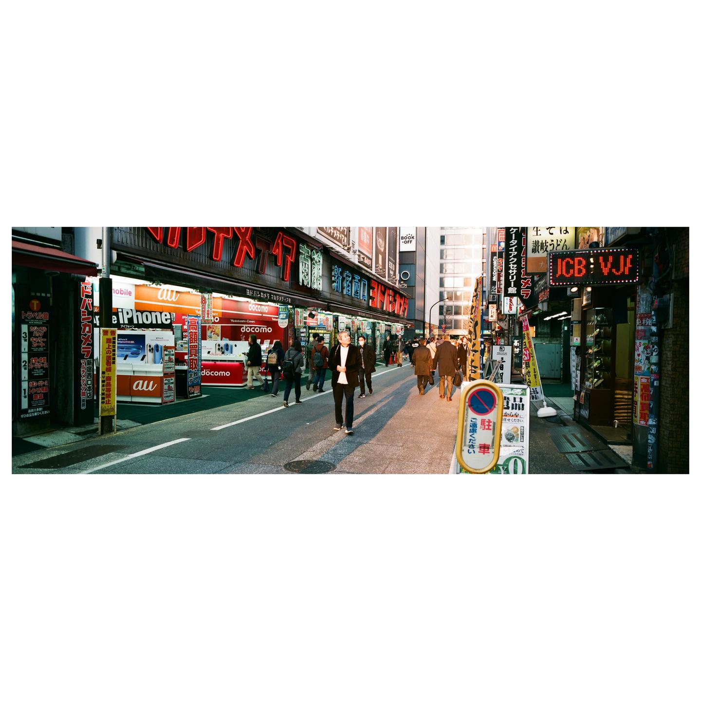 A street in Japan is filled with pedestrians and neon signs.