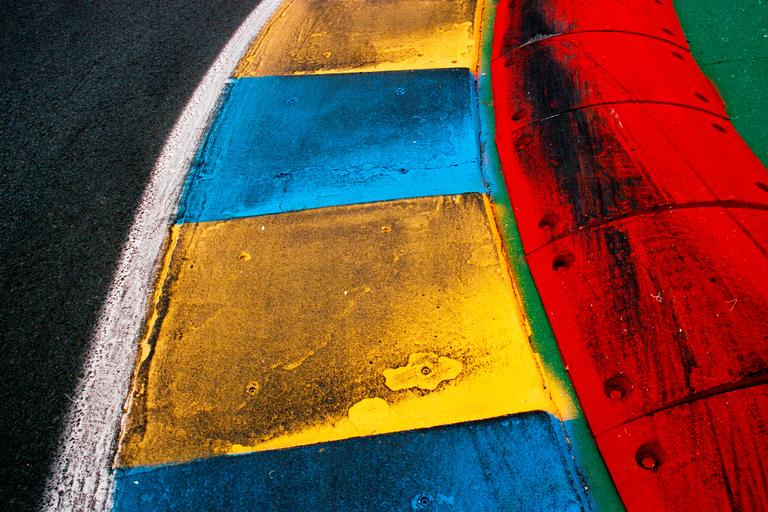 A colorful curb with red, yellow, and blue sections is next to a black asphalt track.