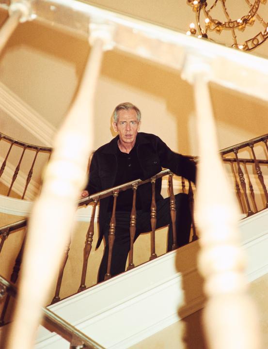 A man stands on a wooden staircase looking up at the camera.
