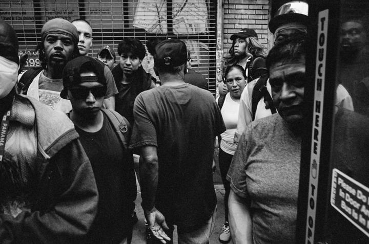 A crowd of people stands on a street in New York City.
