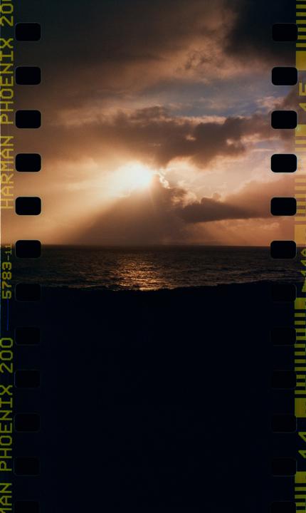 Sunlight breaks through clouds over a dark ocean, creating a bright reflection on the water.