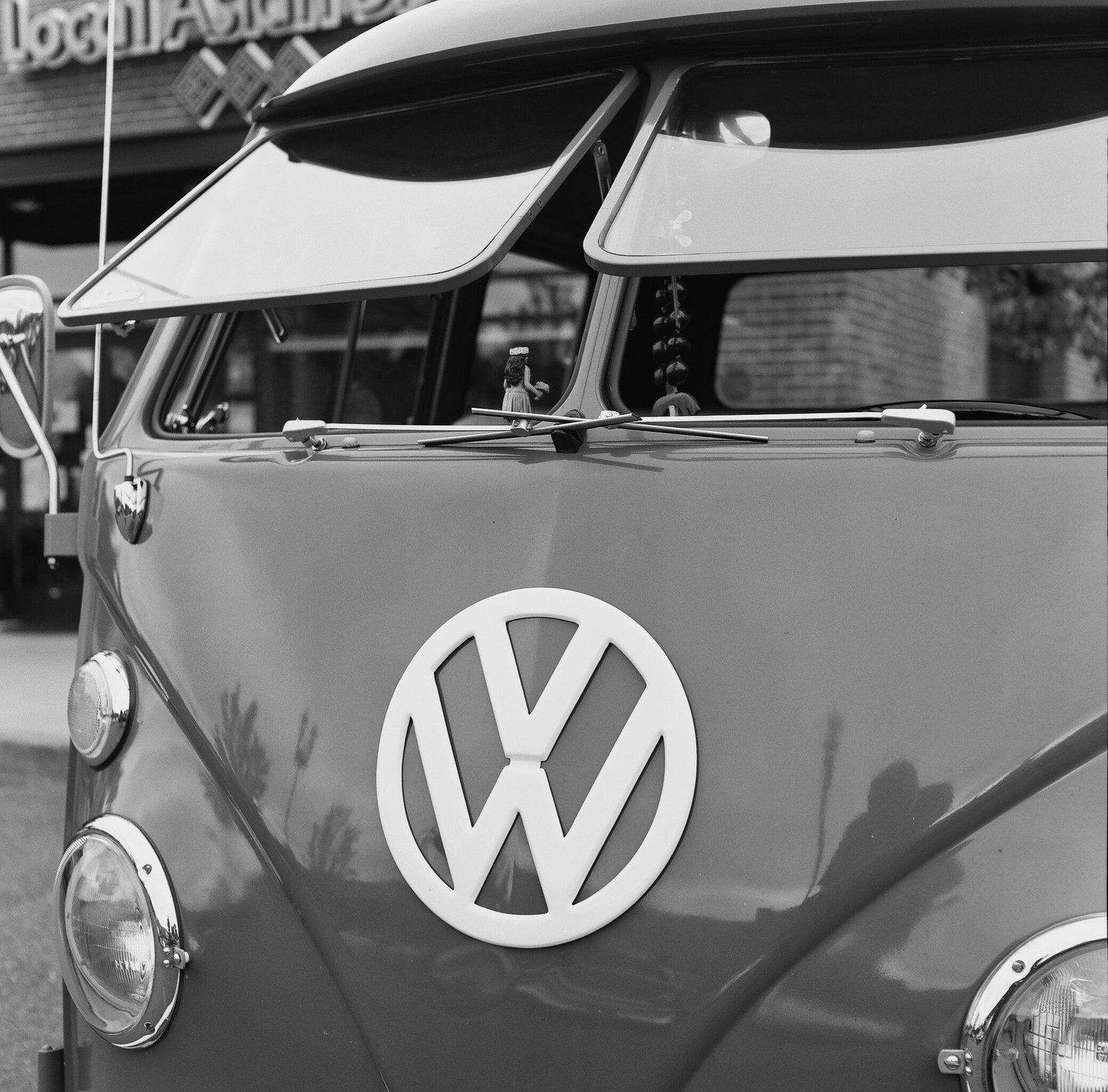 A Volkswagen van with its front windows open is parked on a street.