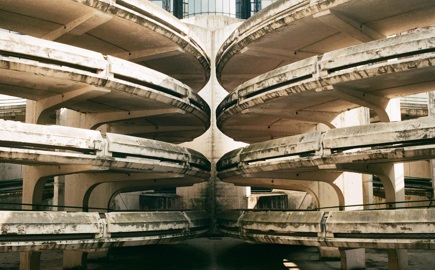 A concrete parking garage with curved ramps is reflected to create a symmetrical abstract composition.