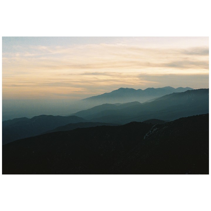 A hazy mountain range is visible under a cloudy sky at dusk.