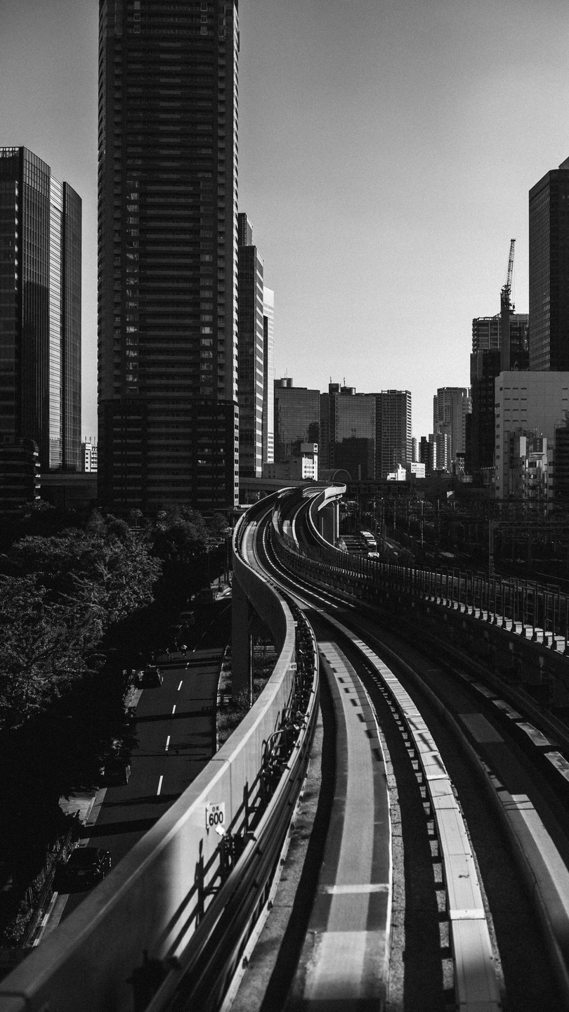 A railway track curves through a city with tall buildings and trees.