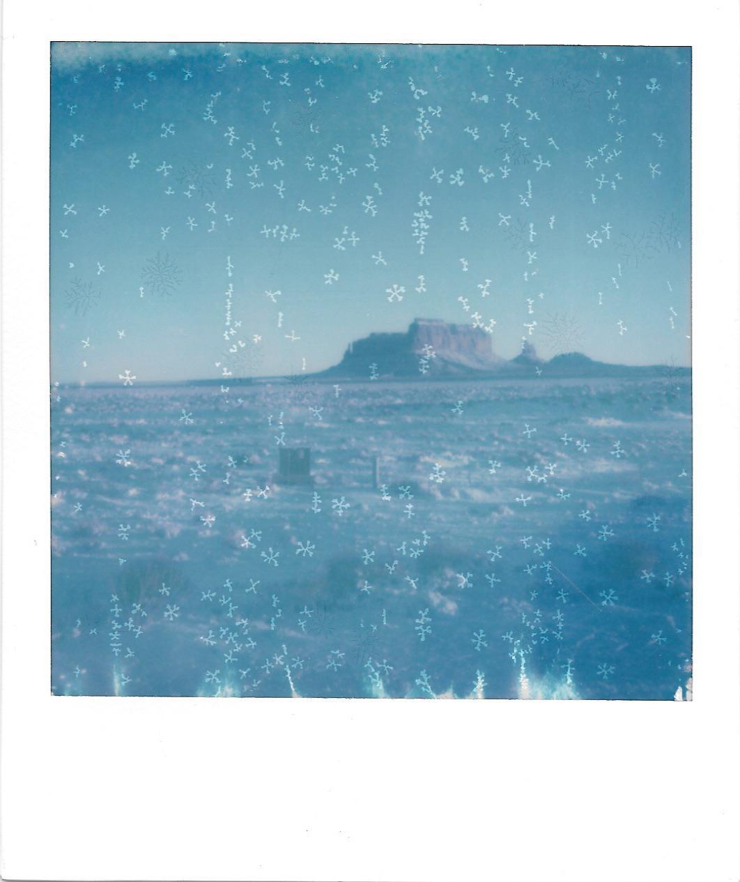A wide, flat landscape with a mesa in the distance is covered in ice crystals.
