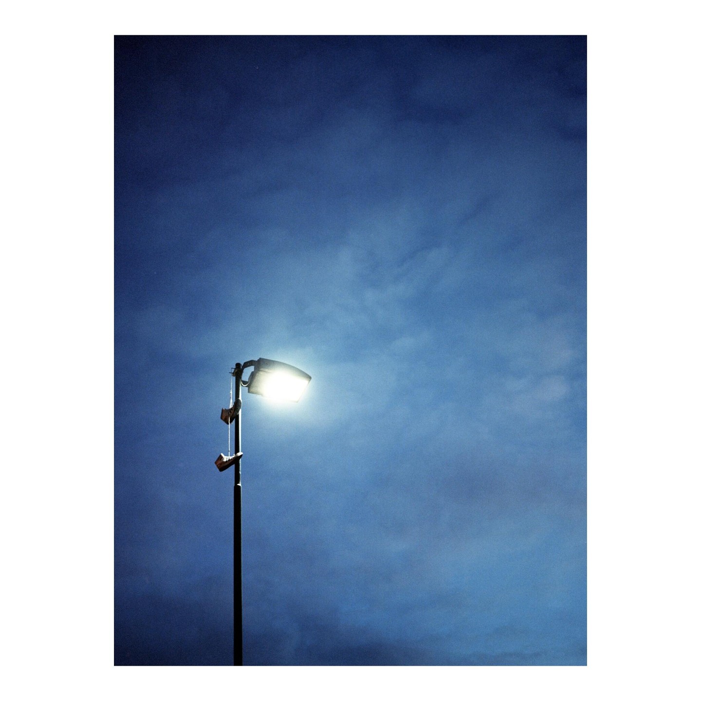 A street light illuminates a dark blue sky with clouds.