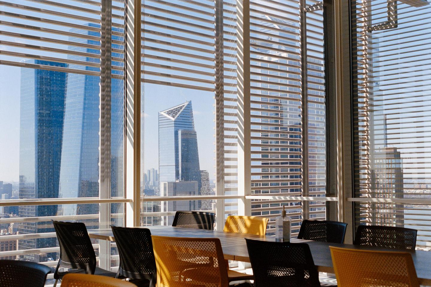 A cafeteria with a large window overlooks a cityscape with several skyscrapers.