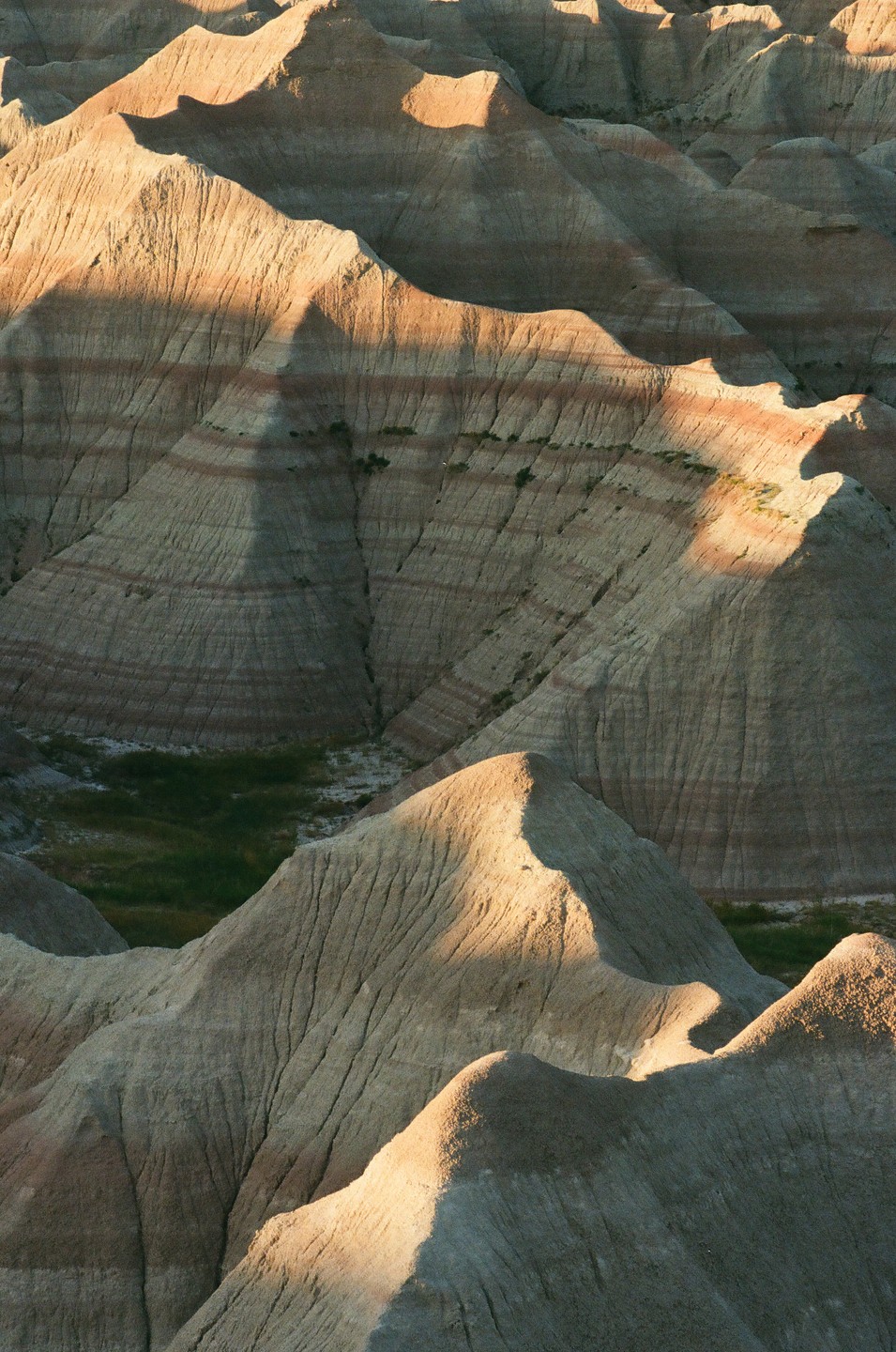 Sunlight illuminates the ridges and valleys of a badlands landscape.