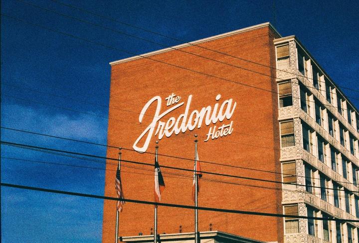The Fredonia Hotel sign is visible on the side of a brick building with flags and power lines in front.