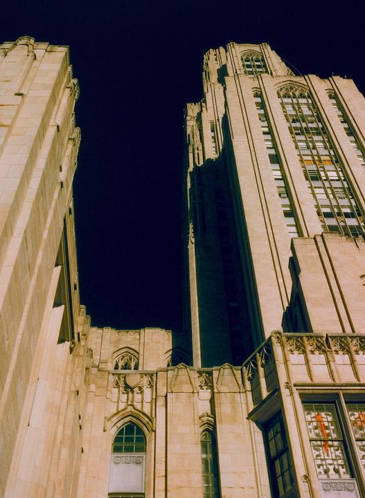 Two tall, ornate stone buildings with many windows rise against a dark night sky.