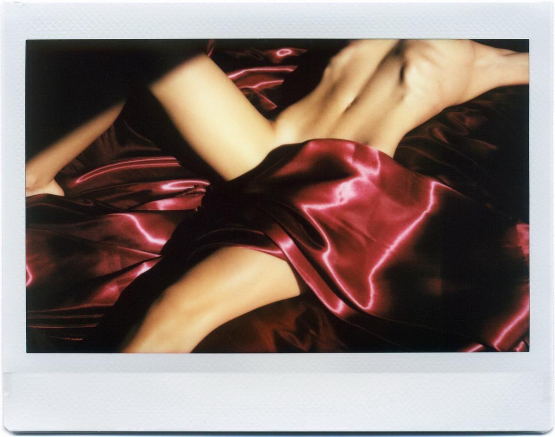 A person's body is partially covered by a red satin sheet.