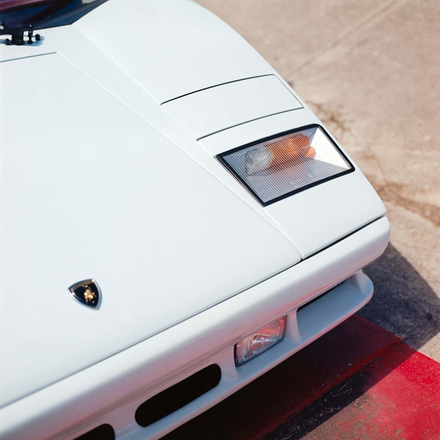 A white car is parked on a red and gray surface.