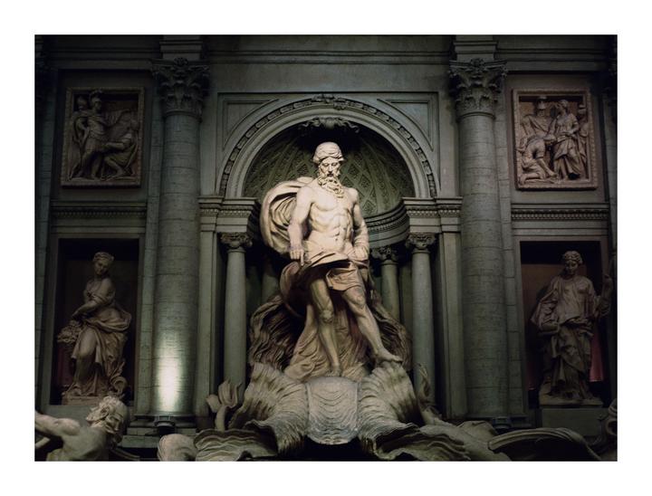 A large stone statue of a man stands in a niche, surrounded by other statues and architectural details.