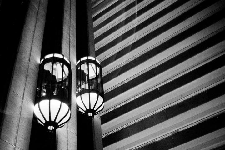 Two glowing elevators are visible next to a building with many floors.