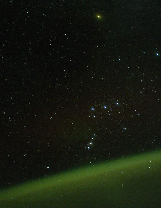 The Orion constellation is visible above a green atmospheric glow.