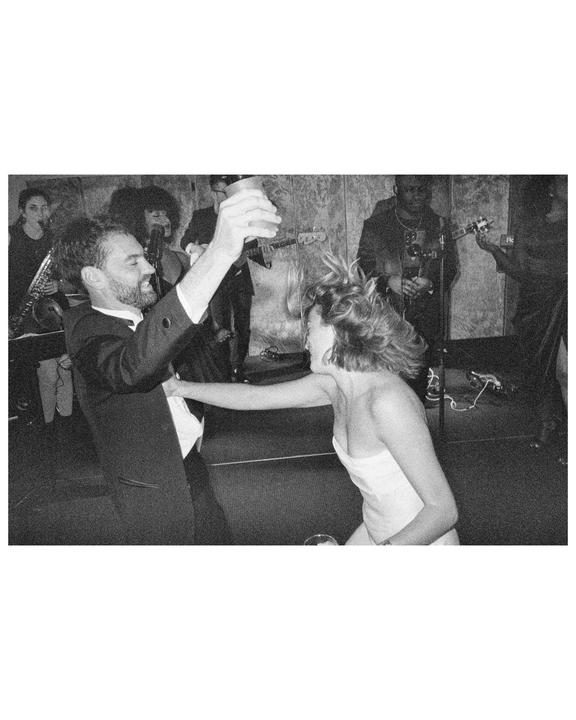 A man and a woman dance energetically in front of a band at a wedding reception.