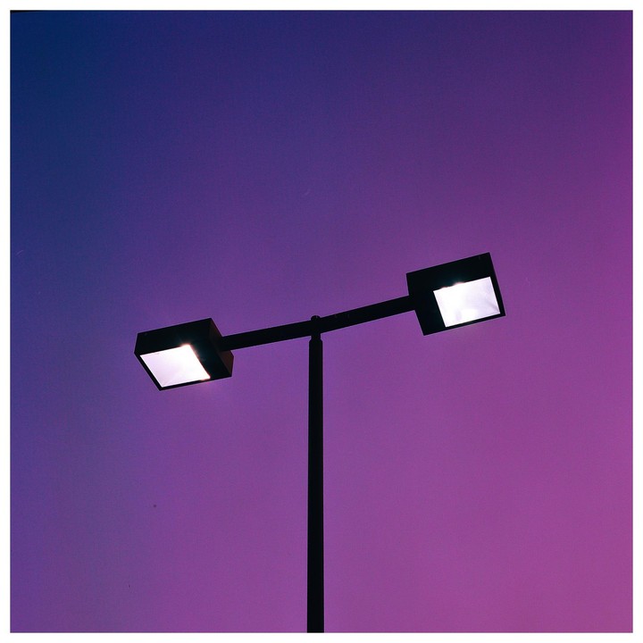 A street light with two square lamps is silhouetted against a purple and blue gradient sky.