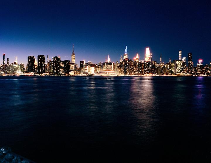 A city skyline with illuminated buildings is visible across a body of water at night.