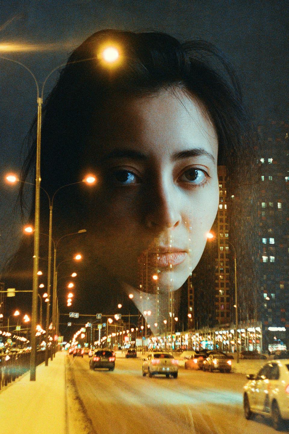 A woman's face is superimposed over a night street scene with cars and buildings.