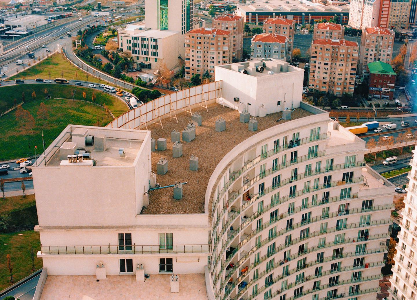 An aerial view shows a curved apartment building next to a highway and other buildings.