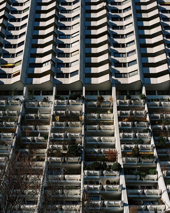 A tall building with many balconies and windows is shown from a low angle.