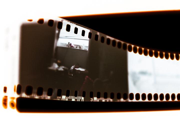 A strip of film shows a blurry image of an interior space with a window.