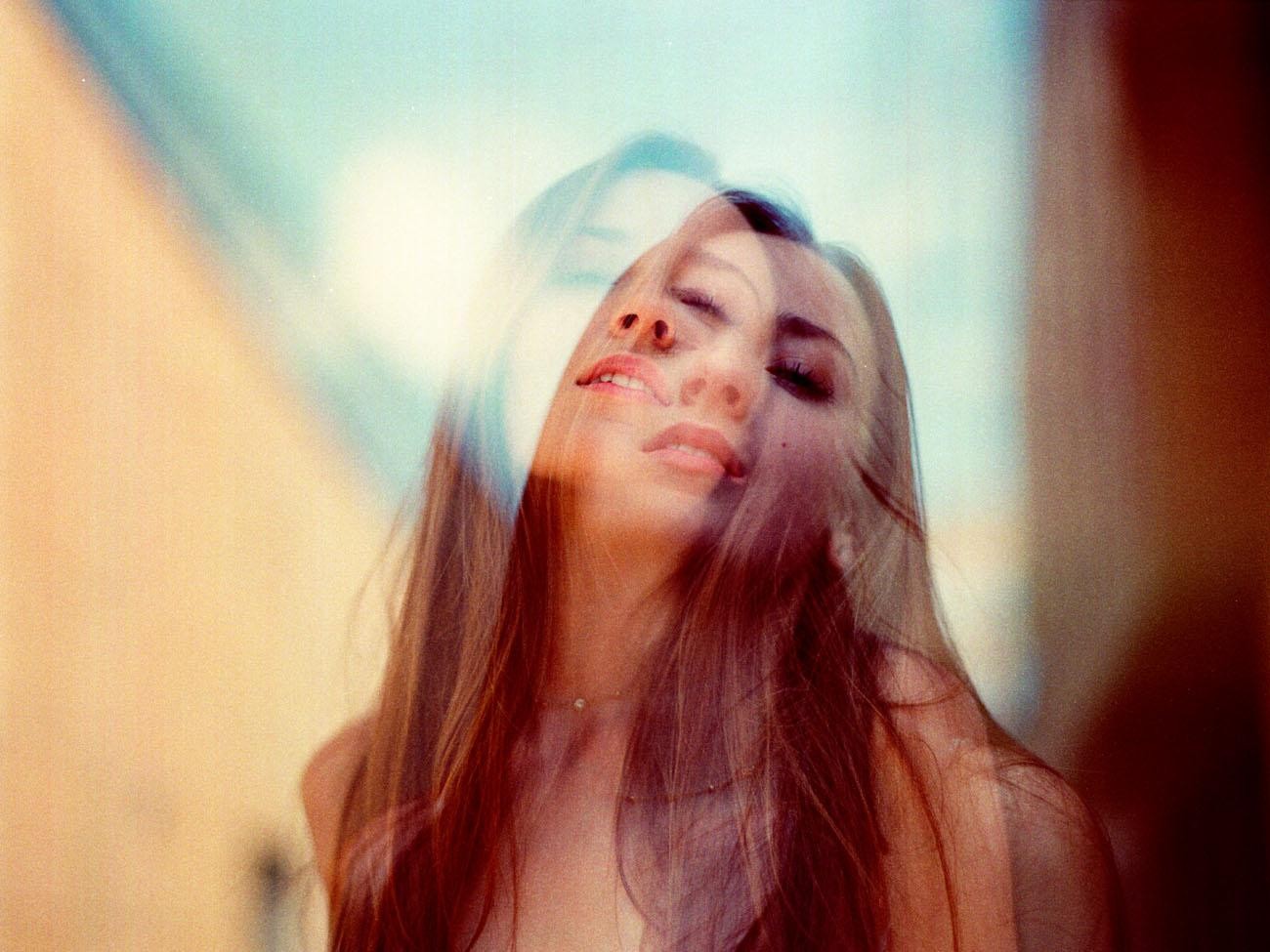 A double exposure portrait shows a woman with her head tilted back and eyes closed, with a faint overlay of another face.