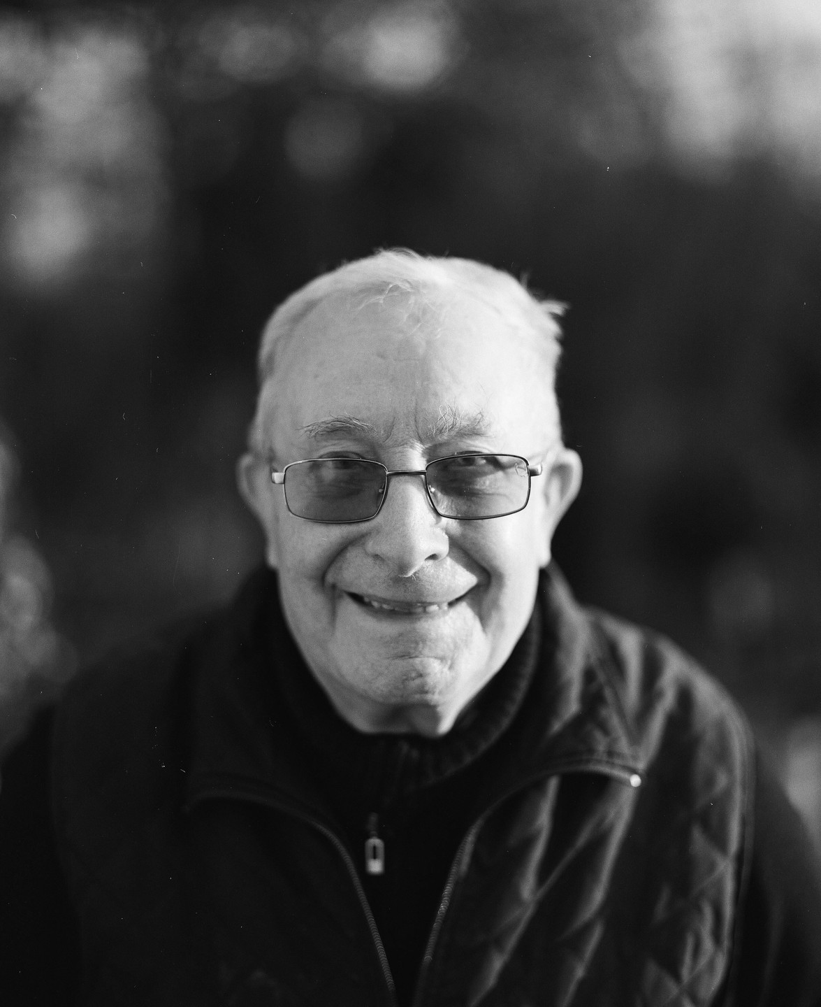 A man with glasses smiles at the camera.