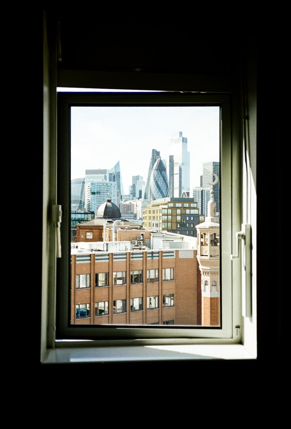 A city skyline with modern skyscrapers and older buildings is visible through an open window.